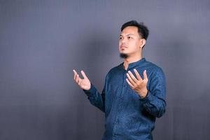 Asian Muslim Man praying to God against on gray background photo