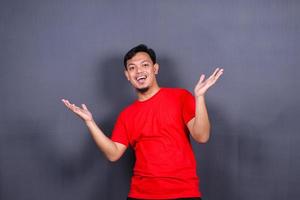 Portrait of an excited asian man standing with raised hands and looking at camera isolated on gray background celebrating succes, victory. photo