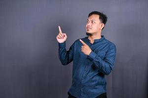 Young asian man isolated on gray background pointing to the side to present a product photo