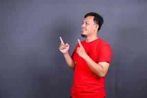 Portrait of an excited asian man standing with raised hands and looking at camera isolated on gray background celebrating succes, victory. photo