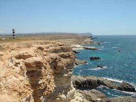 hermoso paisaje de acantilado con faro y olas de mar en el fondo. foto