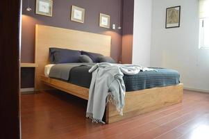 bed base, bedroom with mat on the floor, clay pot in the background, wooden credenza and mirror. photo