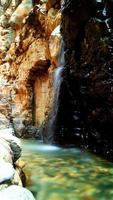 fuente de agua, piedras mojadas goteando agua, pequeño lago de agua turquesa, verdor, rayos de luz filtrados foto