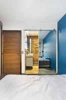 dormitorio, habitación, al fondo se ve un baño, con puerta corredera espejada, puerta de madera foto