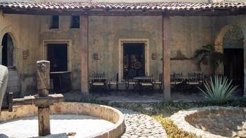 mechanical distillery wheel, roof tiles, tables and chairs in the background, old distillery, mexico photo