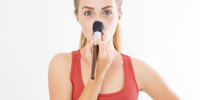 Closeup of happy young woman face with make up brush isolated on white background. Beauty girl skin care concept. Copy space. Banner photo