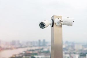 Modern CCTV camera against city and sky background. surveillance, video record and monitoring concept photo