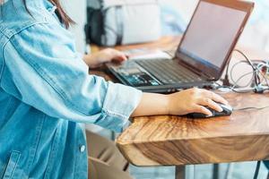 Woman hand holding mouse during using computer laptop in workplace. Business and technology concept photo