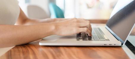 woman using laptop, freelance woman typing keyboard computer notebook in cafe or modern office. technology, digital online and network concept photo