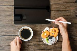 feliz día de halloween con galletas, café y tabletas. compras en línea, hola octubre, otoño otoño, concepto festivo, fiesta y vacaciones foto