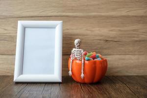 Orange pumpkin bowl and candies on table and frame with copy space for text. Happy Halloween day, Hello October, fall autumn season, Festive, party and holiday concept photo