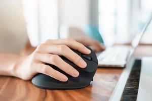 mano de mujer usando un mouse ergonómico de computadora, prevención del dolor de muñeca porque trabaja mucho tiempo. tenosinovitis de de quervain, síntoma de intersección, síndrome del túnel carpiano o concepto de síndrome de oficina foto