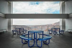 Brutalist concrete architecture, large space overlooking a ravine, blue dining benches. Beam framing the landscape photo