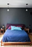 bed base, bedroom with mat on the floor, clay pot in the background, wooden credenza and mirror. photo