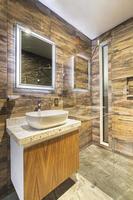 bathroom with luxury finishes, main mirror with led light from behind, white ceramic washbasin photo