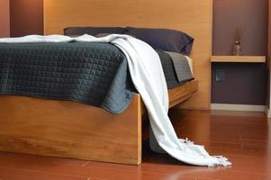 bed base, bedroom with mat on the floor, clay pot in the background, wooden credenza and mirror. photo