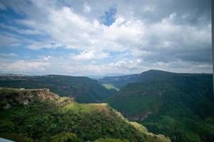 ravine trees and vegetation, view of several mountains at different depths, blue sky and few clouds, mexico photo