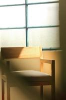 una silla de madera moderna con estructura de madera, la luz del sol entra por la ventana iluminando la silla foto