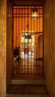 entrance to an old house, behind a lighted chandelier, stone floor and concrete walls, orange light in the space, mexico photo