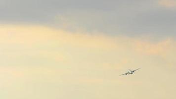 Long shot of a commercial aircraft turning in the sunset light. Climb after takeoff. Tourism and travel concept video