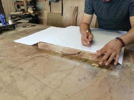 un carpintero anónimo trabajando en un nuevo proyecto en su taller. vista superior de la mesa del hombre irreconocible dibujando n foto