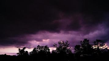 purple sky, cloudy, black silhouette of trees and people looking at the sky photo