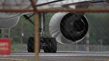 vicino su di il atterraggio Ingranaggio ruote, pneumatici su un' moderno gemello motorizzato passeggeri aereo. aereo è rullaggio lungo il aeroporto grembiule video