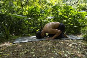 joven latino arreglando su colchoneta de yoga, dentro de un bosque en una llanura, contacto directo con la naturaleza, méxico foto