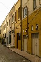 calzada, acera y adoquines en un pequeño barrio, contiguas a casas de color amarillo y mostaza, al atardecer foto