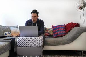 hombre trabajando desde casa con una laptop en la sala de estar foto