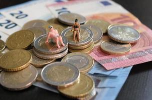 Miniature figurines of a couple relaxing and tanning on a pile of money photo