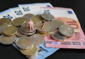 Miniature figurines of a couple relaxing and tanning on a pile of money photo
