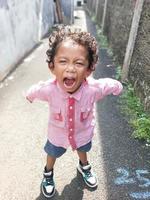 Photo of an expressive boy with curly curls in a red shirt