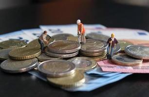 figuras en miniatura de trabajadores que trabajan en un montón de dinero foto