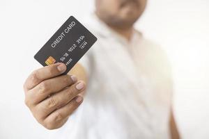 Close-up hand of Asian man holding black credit card in his hand isolated on white background. Concept of trading, social, technology, business. photo