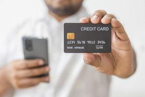 Close-up hand of Asian man wearing white shirt holding black credit card in his hand. isolated on white background. Concept of finance, trading, communication, social, technology, business photo