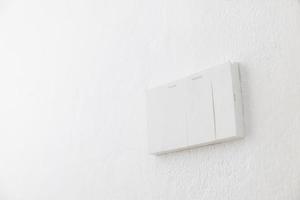 Light switch, Close-up White plastic mechanical switch mounted on a white wall photo