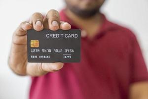 Close-up hand of Asian man wearing red shirt holding black credit card in his hand. isolated on white background. Concept of finance, trading, communication, social, technology, business photo