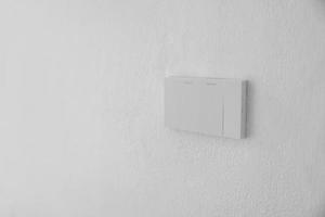 Light switch, Close-up White plastic mechanical switch mounted on a white wall photo