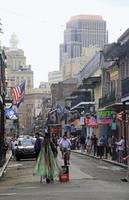 New Orleans, Louisiana, USA, 2018 - A street artist walks on a street in the middle of the French Quarter of New Orleans, Louisiana, with shops and neon lights in the background. photo