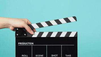 Hand is holding Black clapper board or movie slate on green or Turquoise background. photo