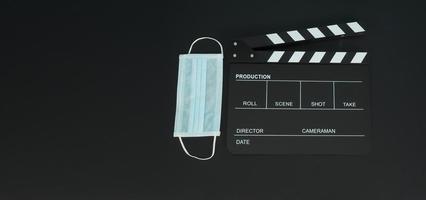 Black Clapper board or movie slate with face mask. it use in video production,movies and cinema industry on black background. photo