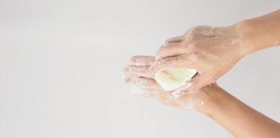 Hands washing gesture with bar soap and foam bubble on white background. photo