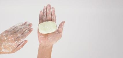 Hands washing gesture with bar soap and foam bubble on white background. photo