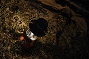 lámpara de aceite antigua en la hierba en el bosque oscuro por la noche, farol de camping nocturno, aislado en el fondo de la hierba verde. foto