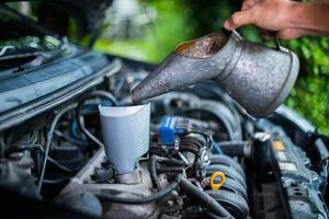 Inspection of the engine and checking the motor oil level, The car is checking the engine oil level, and the mechanic is pouring oil into the engine. photo