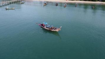 Luftaufnahme von einer Drohne traditioneller thailändischer Longtail-Fischerboote, die im Meer segeln. Draufsicht auf ein Fischerboot im Ozean.