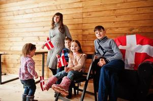 Family with Denmark flags inside wooden house. Travel to Scandinavian countries. Happiest danish people's . photo