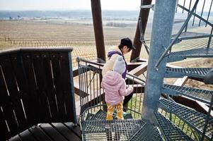 madre con hija parada en la escalera de caracol de la torre de observación de madera. foto