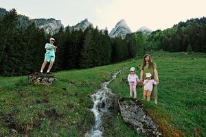 madre con hijos cerca de la fuente de agua limpia de la montaña en vorderer gosausee, gosau, alta austria. foto